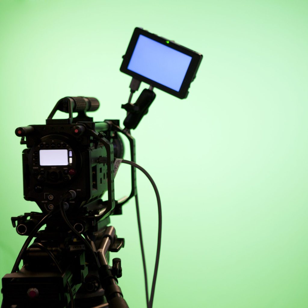 Television camera on green screen background with video display.